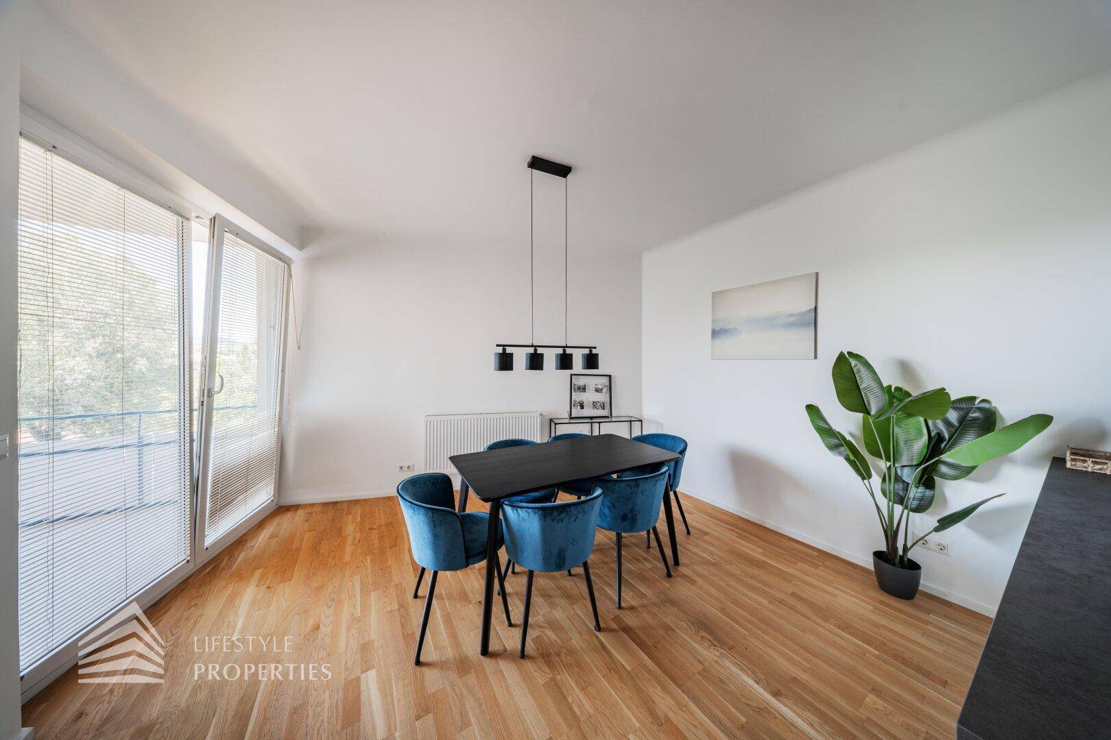 Heller Essbereich mit modernem Mobiliar und direktem Zugang zum Balkon durch eine große Glastür.