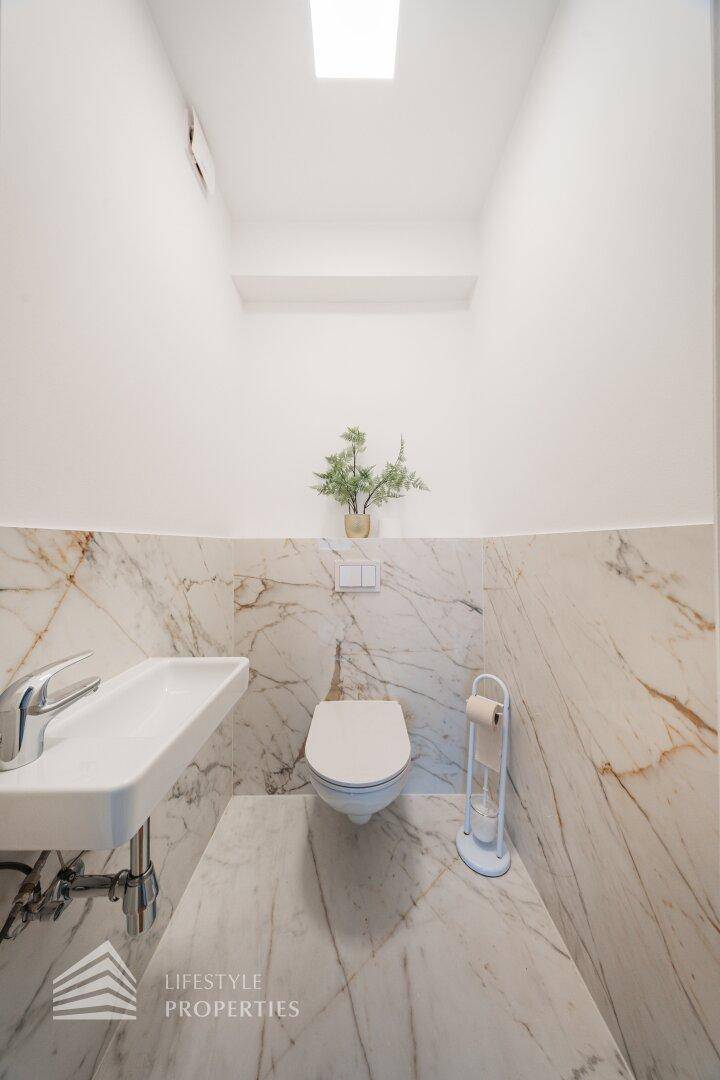 Modernes Gäste-WC mit Marmorfliesen und wandhängendem WC.