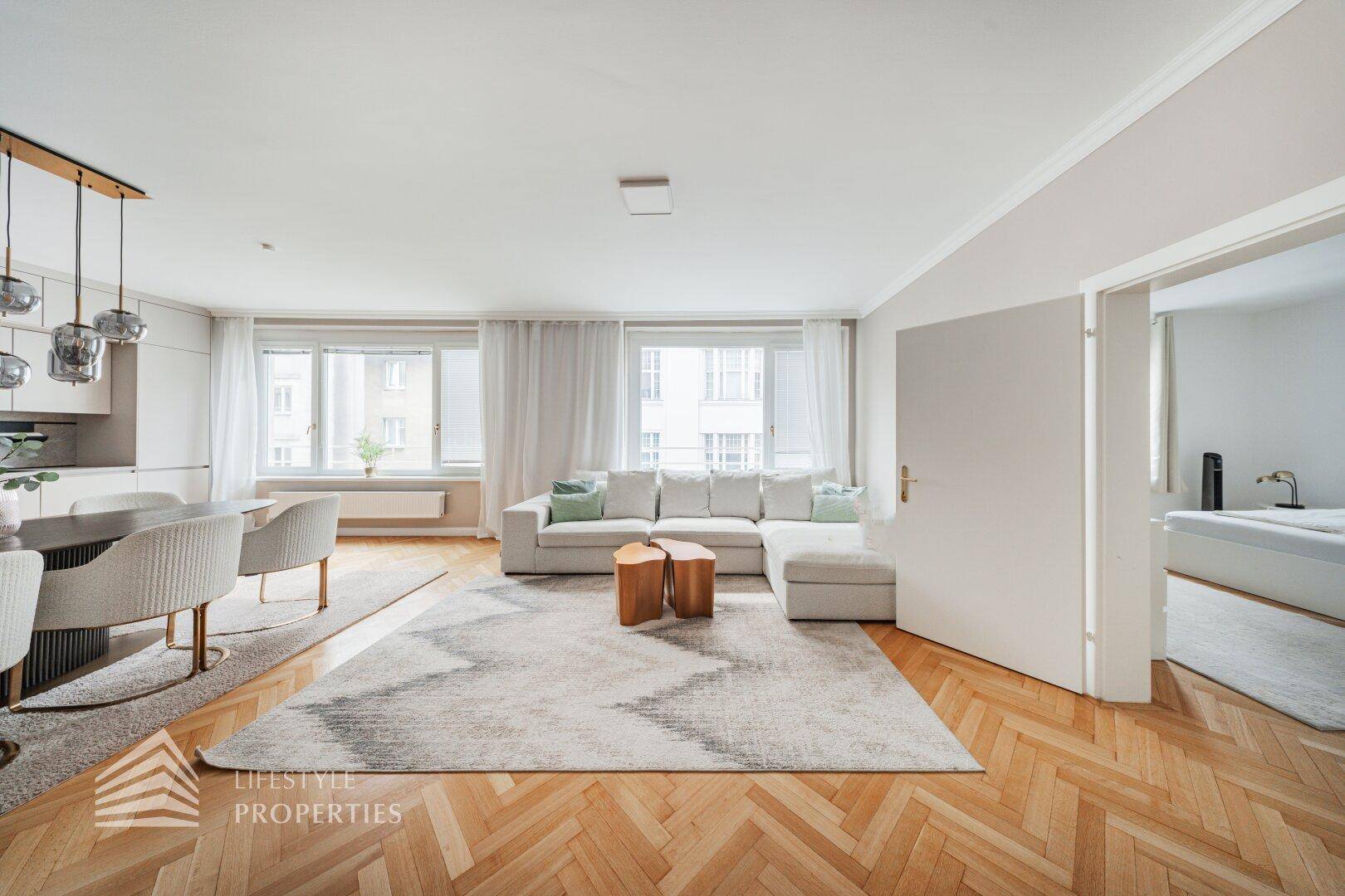 Offener Wohn- und Essbereich mit Sofa, Teppich und Zugang zum Schlafzimmer.
