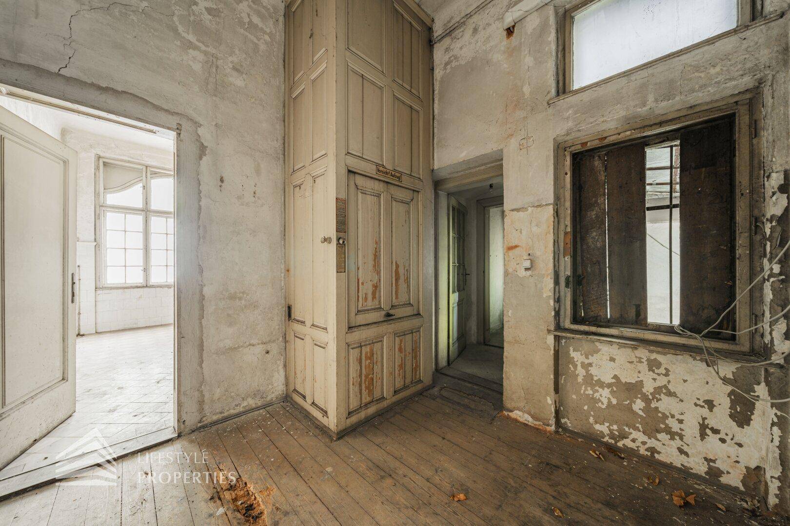 Innenraum mit alter Holzverkleidung und sichtbaren Abnutzungsspuren, der auf eine Renovierung wartet.