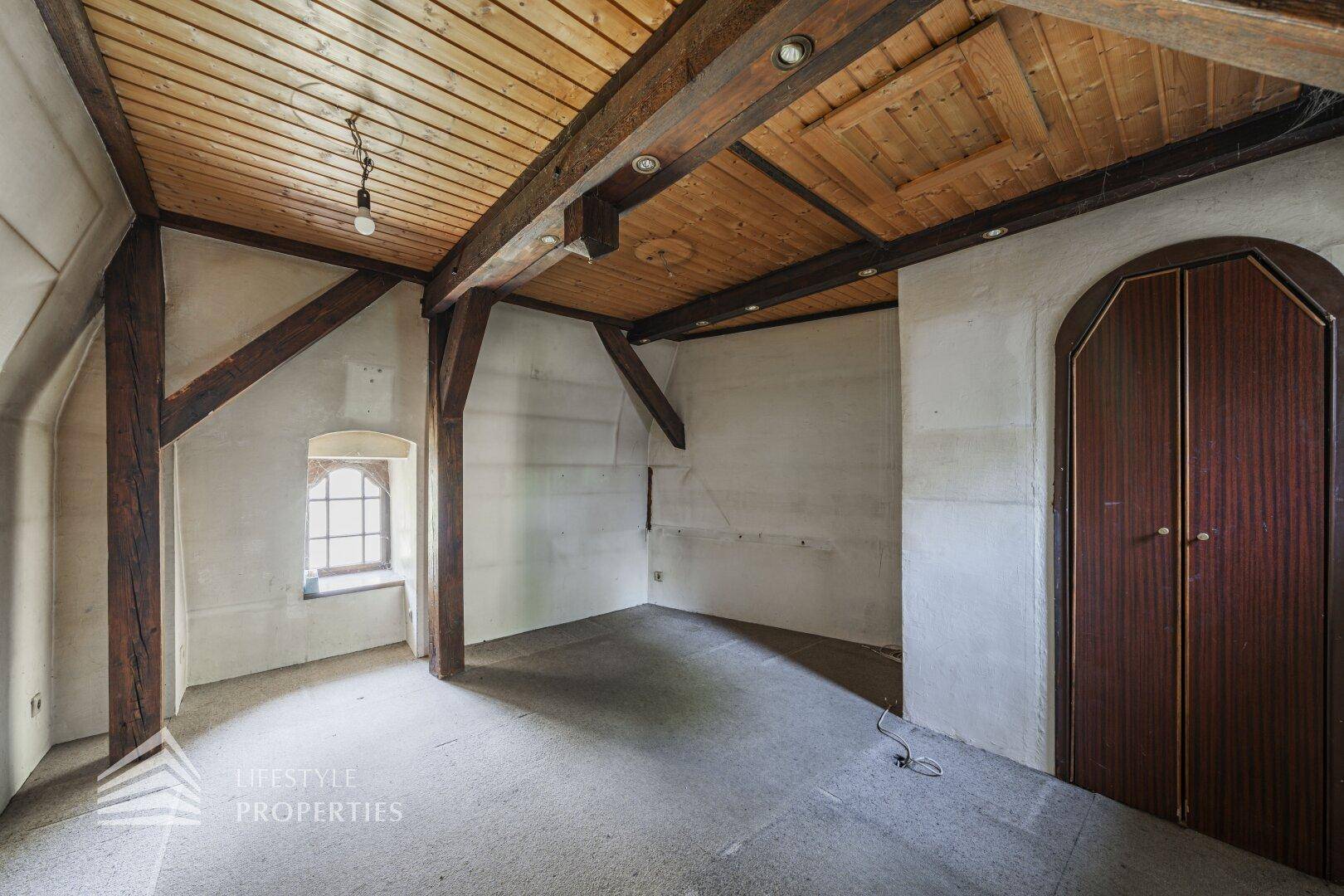 Ausbaufähiger Dachbodenraum mit sichtbaren Holzbalken und schrägen Decken, bietet viel Potenzial.