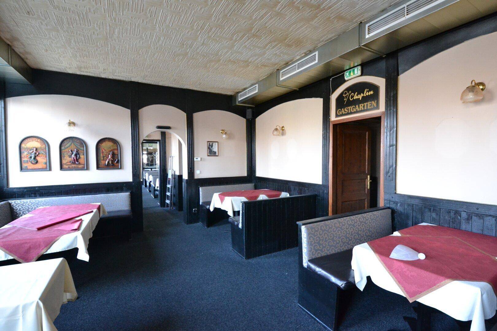 Gemütlicher Restaurantbereich mit dunklen Holzvertäfelungen, gepolsterten Sitzbänken und einem Ausgang zum Gastgarten.