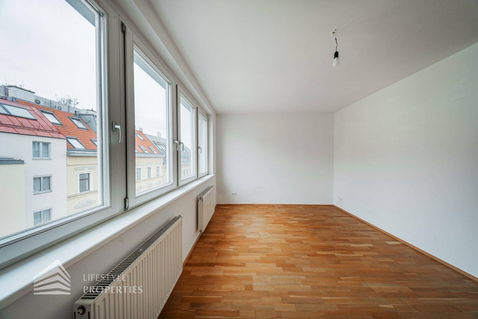 Geräumiges Wohnzimmer mit vielen Fenstern, die viel Tageslicht hereinlassen und Stadtblick bieten.
