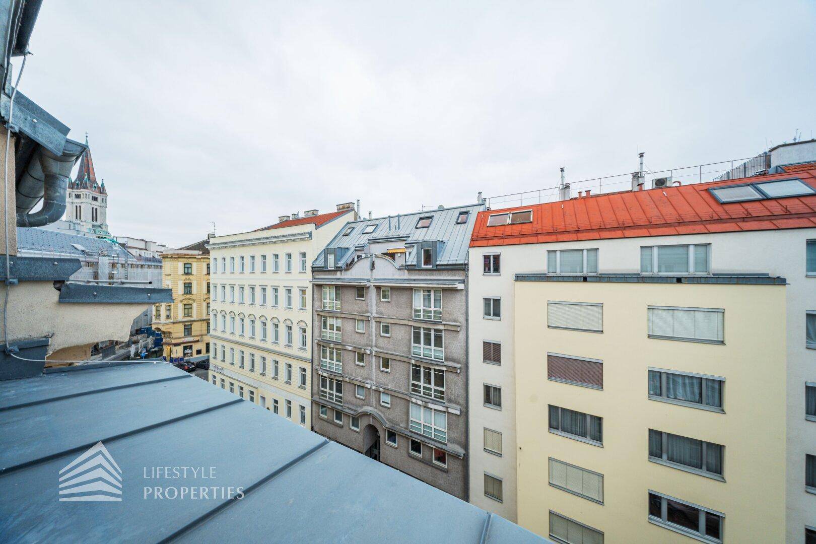 Blick über die Dächer der Stadt mit historischen Gebäuden und modernen Dachfenstern.