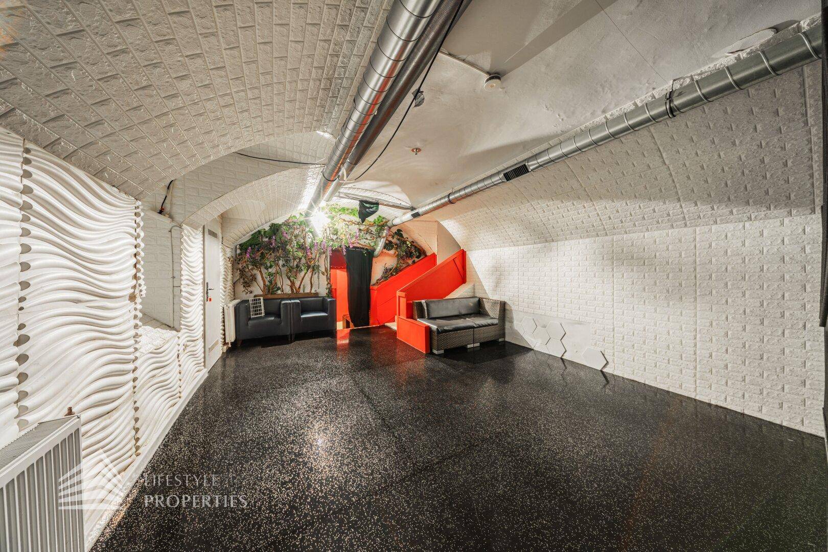 Geräumiger Lounge-Bereich mit bequemen Sofas, gewellter Wandgestaltung und industriellem Decken-Design.