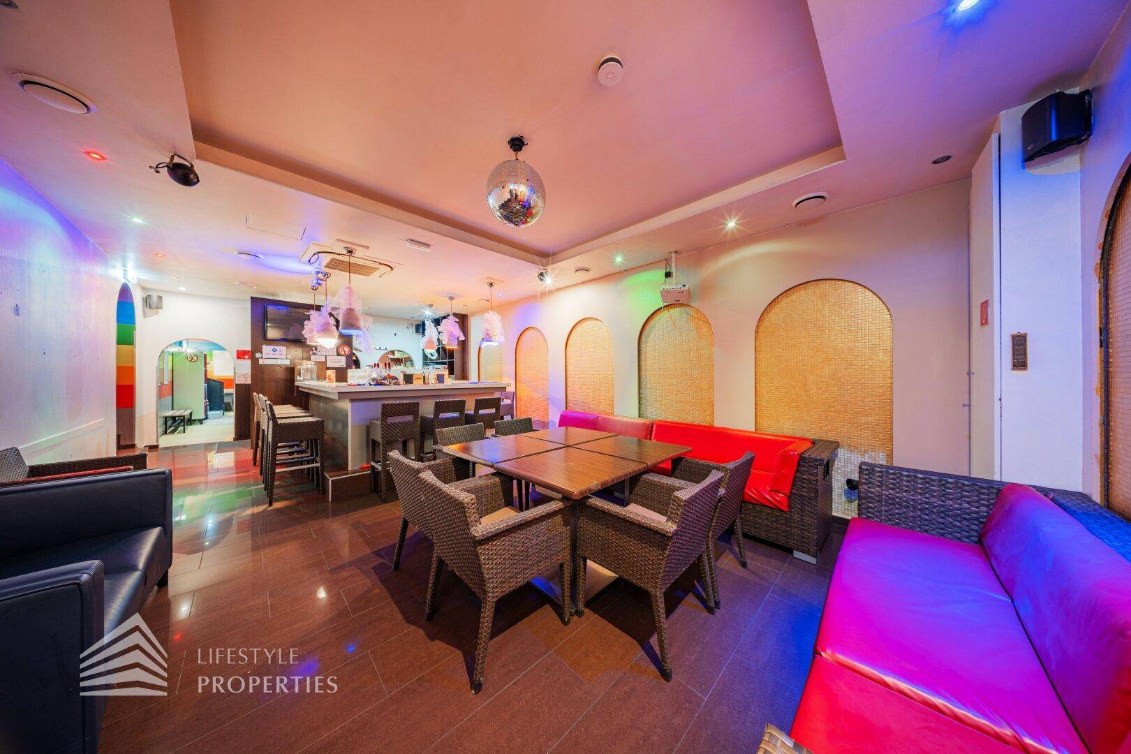 Großer Bar-Lounge-Bereich mit verschiedenen Sitzgelegenheiten, Theke und stimmungsvoller Beleuchtung.