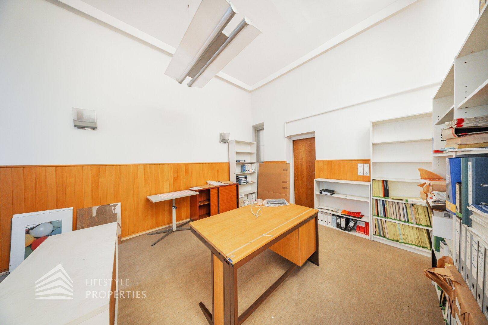 Funktionales Büro mit Holzvertäfelung, Regalen und einem großen Schreibtisch, gut organisiert.
