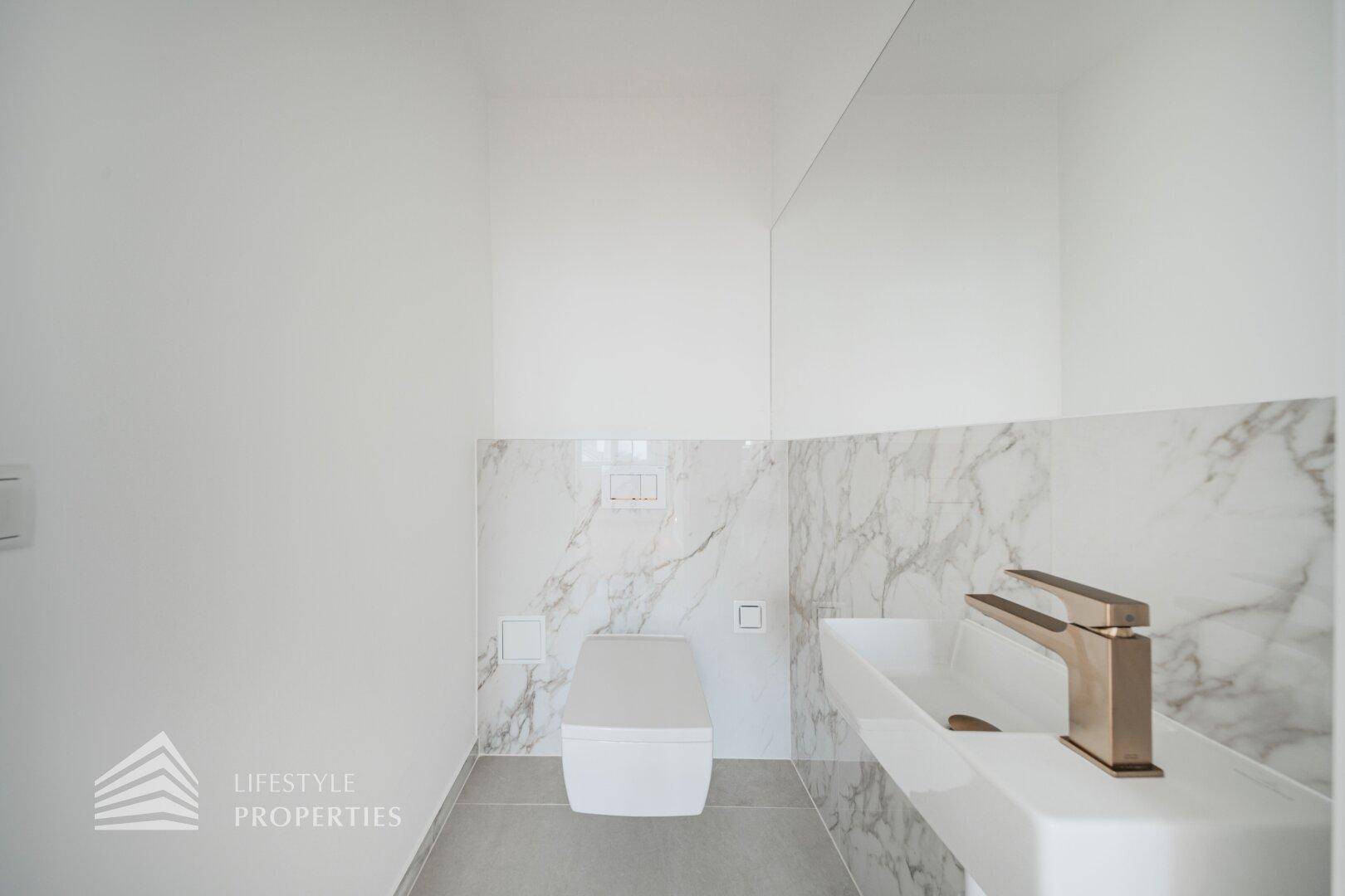 Modernes Gäste-WC mit Marmorfliesen, wandhängender Toilette und elegantem Einzelwaschbecken.