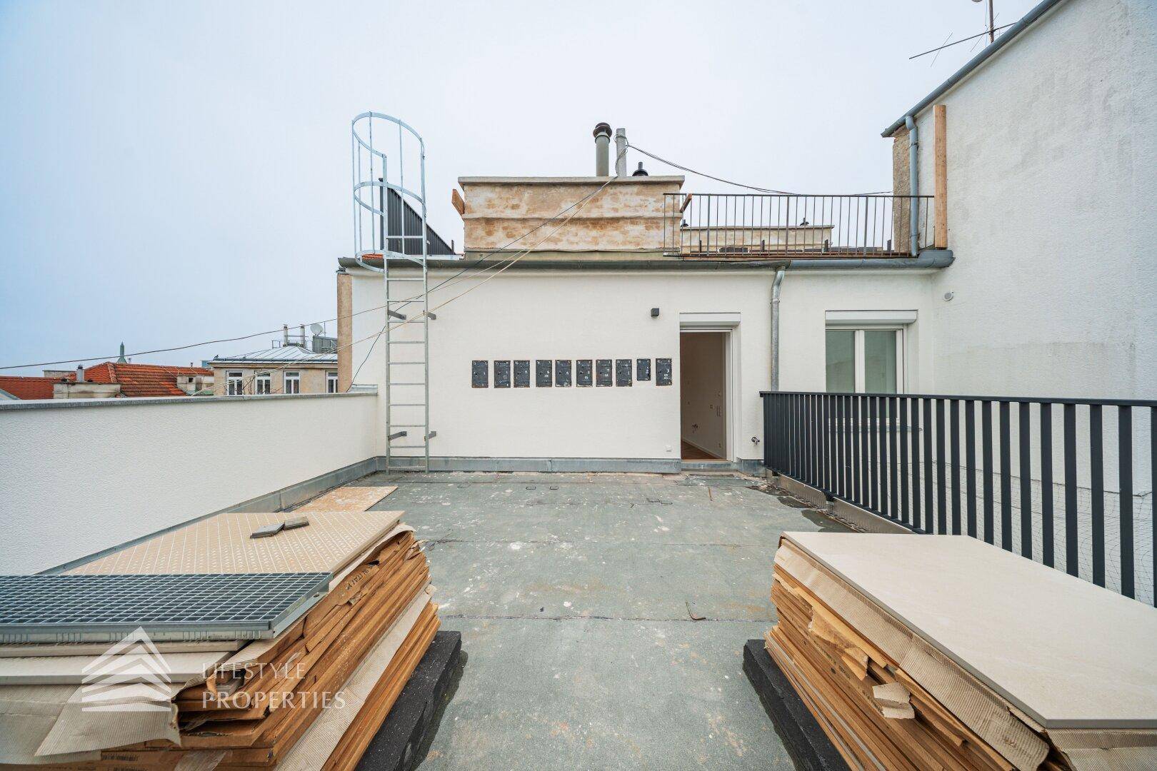 Weitläufige Dachterrasse mit Zugang zum Gebäude und Panoramablick über die Stadt.