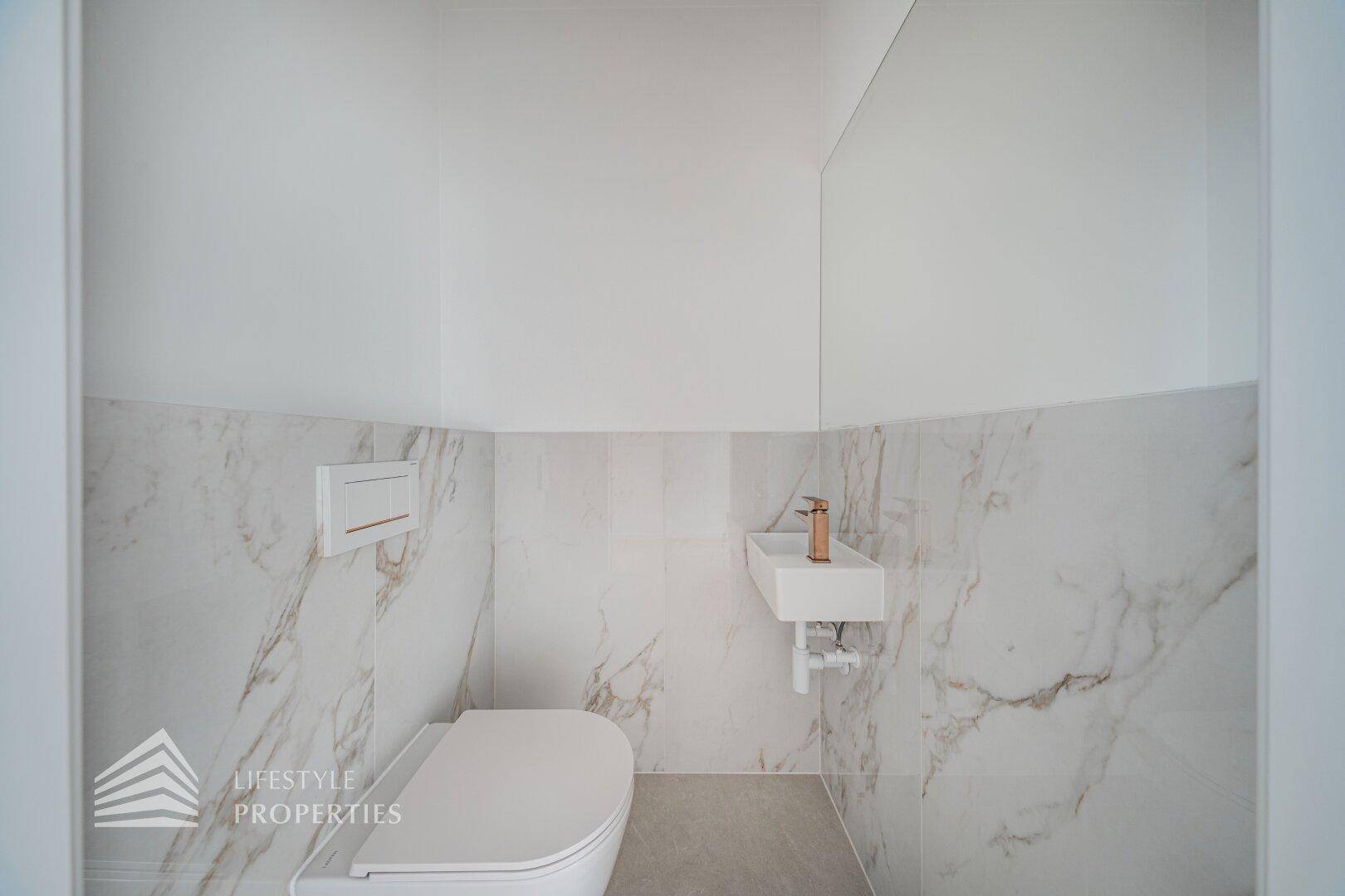 Modernes Gäste-WC mit Marmoroptik-Fliesen, Wand-WC und kleinem Waschbecken.