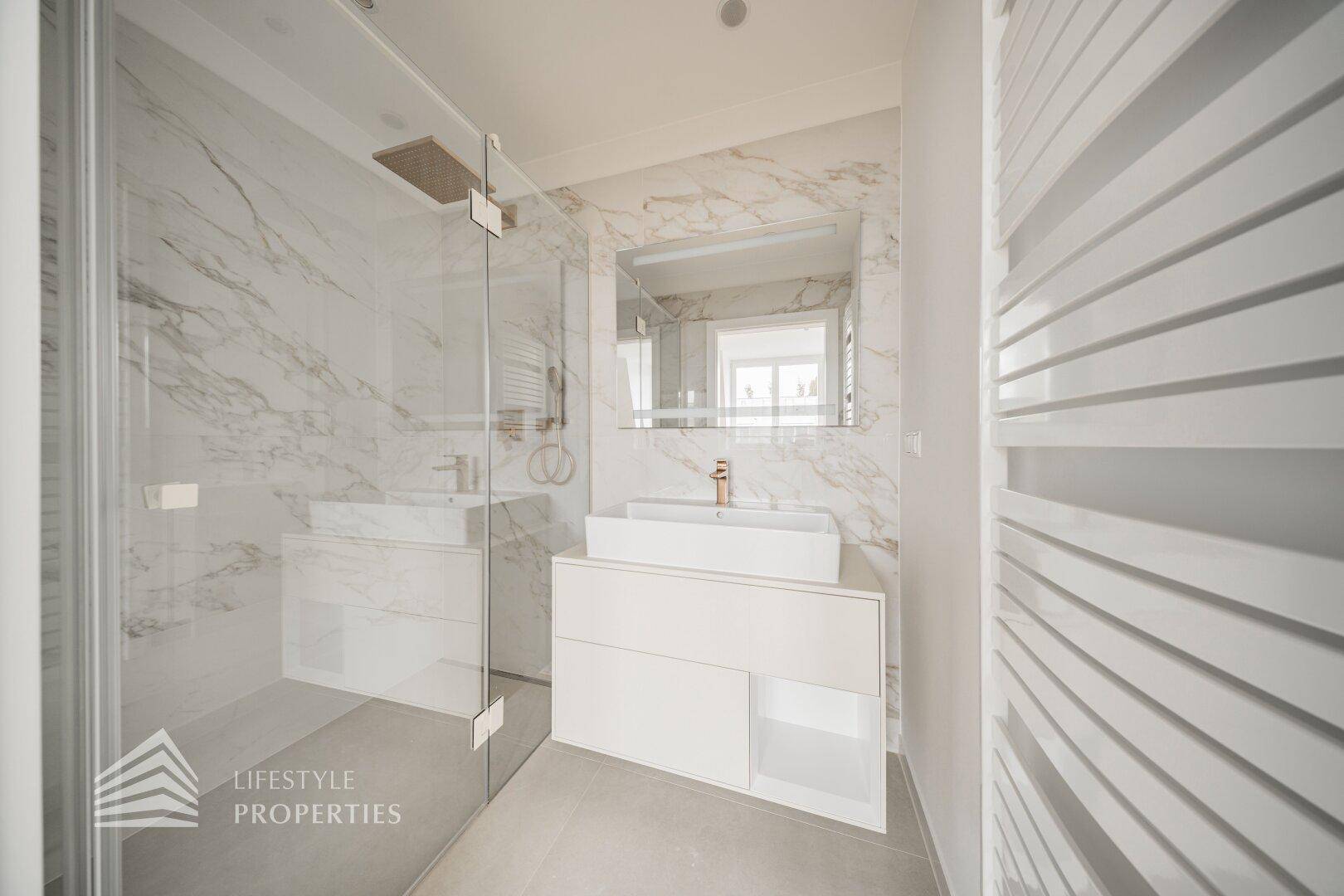 Elegantes Badezimmer mit begehbarer Dusche, modernem Waschtisch und Marmoroptik-Fliesen.
