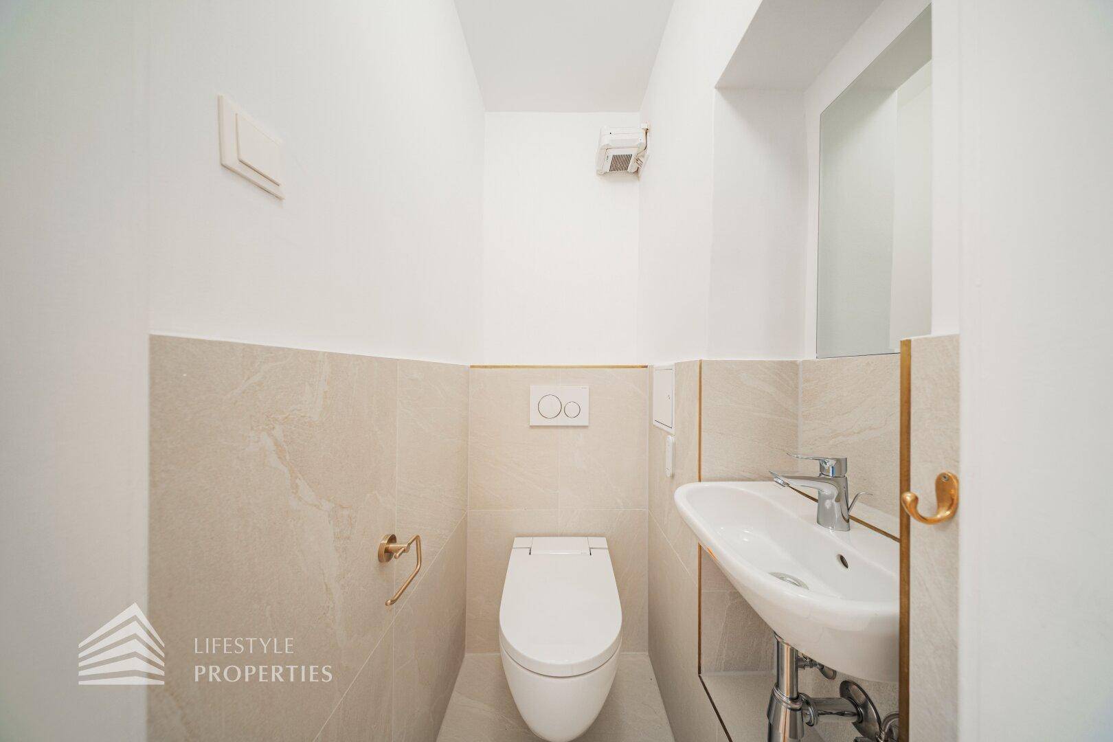 Modernes Gäste-WC mit Waschtisch, Wand-WC und hellen Fliesen.