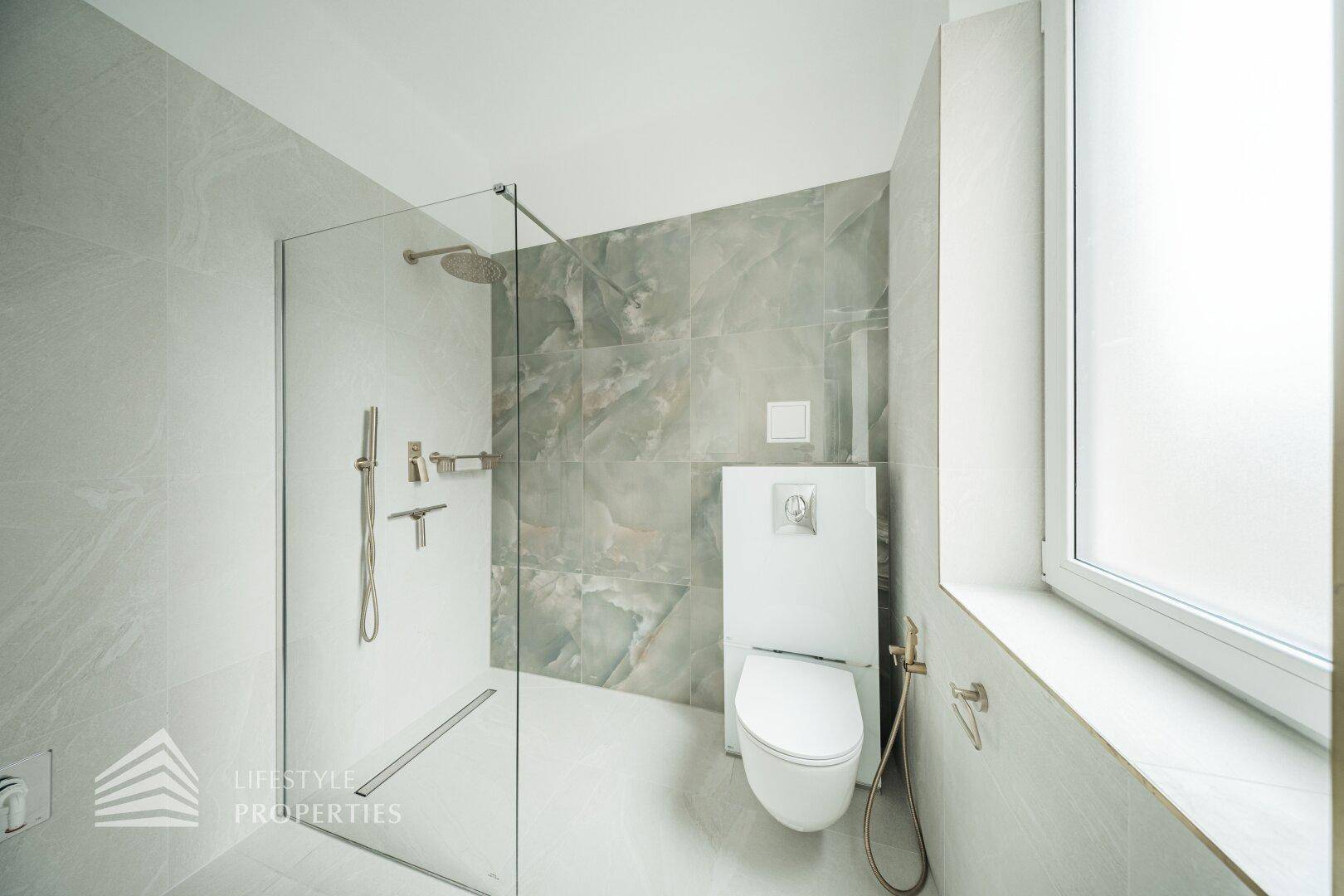 Modernes Badezimmer mit ebenerdiger Dusche, WC und stilvollen grauen Fliesen.