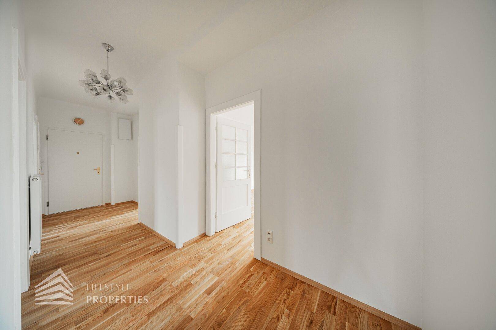 Heller Flur mit Parkettboden und Zugang zu verschiedenen Räumen der Wohnung.