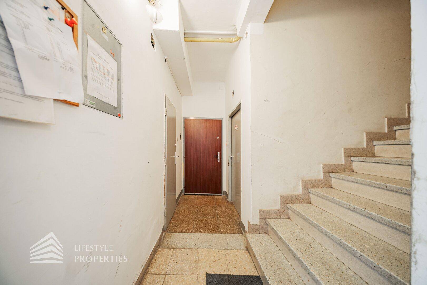 Treppenhaus mit Terrazzoboden und mehreren Wohnungstüren, die zu den einzelnen Einheiten führen.