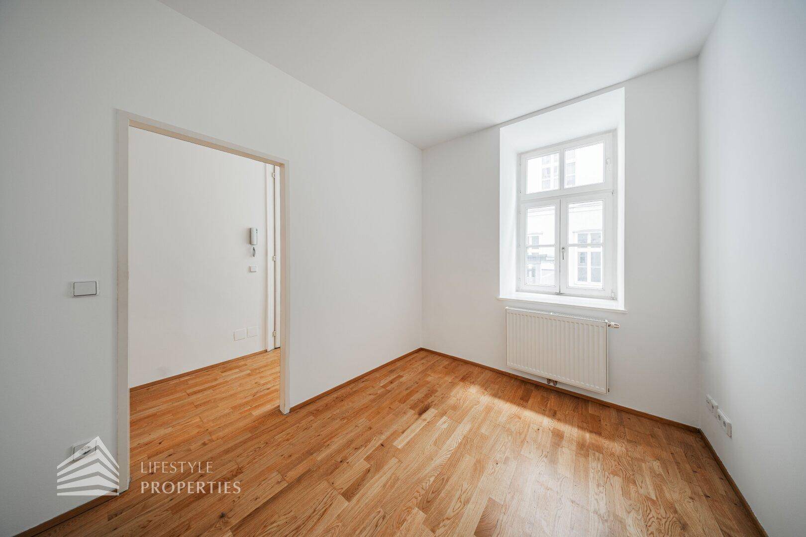 Ruhiges Zimmer mit Parkettboden und Fenster, bietet eine gemütliche Atmosphäre.