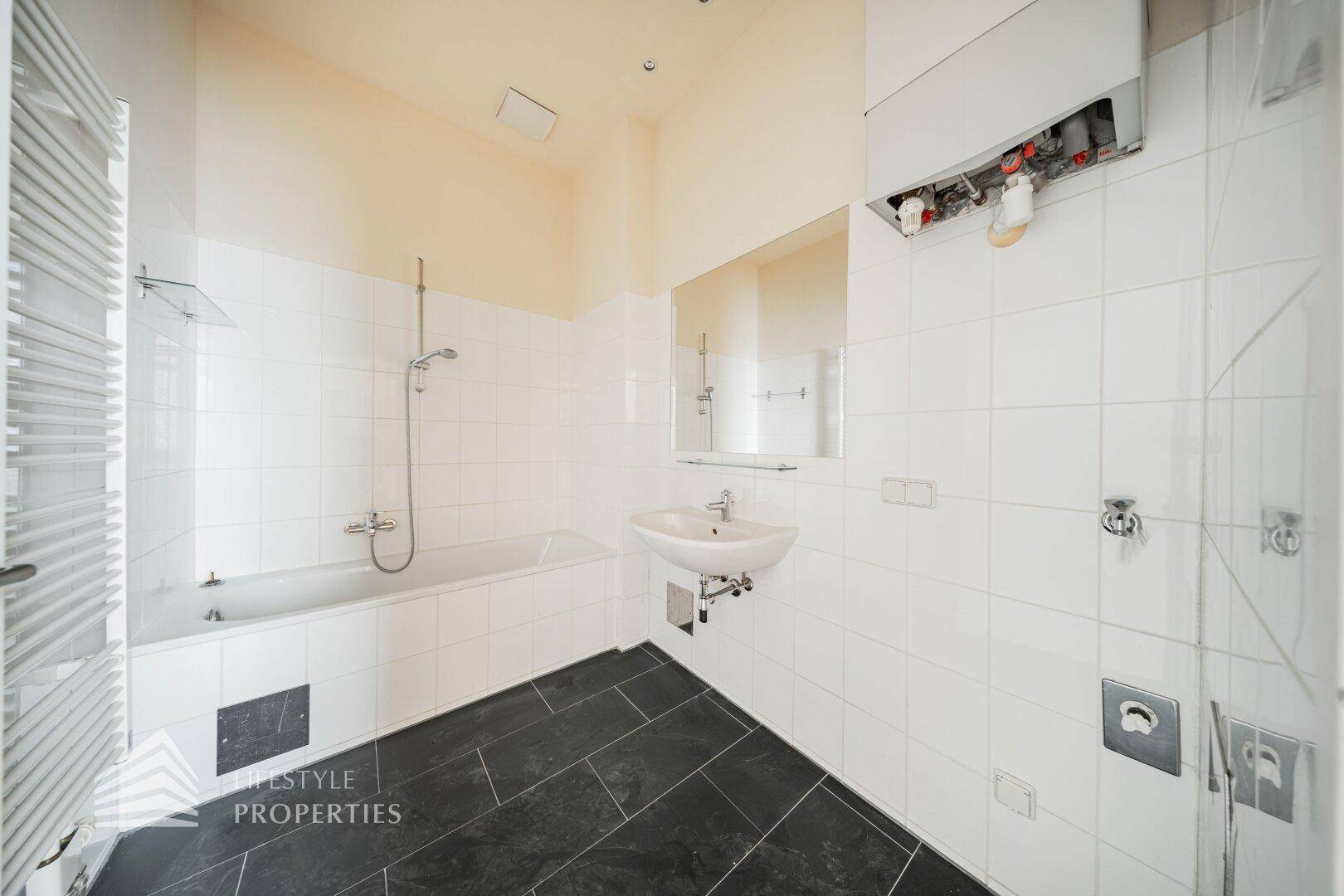 Funktionales Badezimmer mit Badewanne, Dusche, Waschbecken und beheiztem Handtuchhalter.