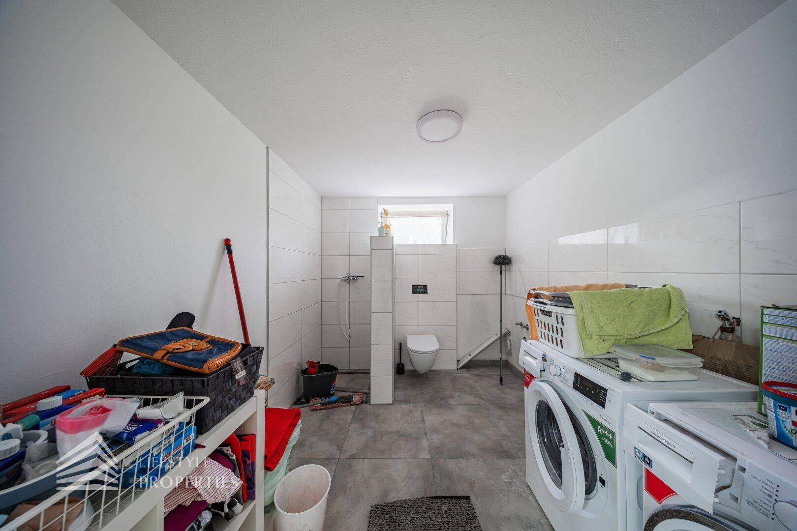 Geräumiger Hauswirtschaftsraum im Untergeschoss mit Waschmaschinen und WC.
