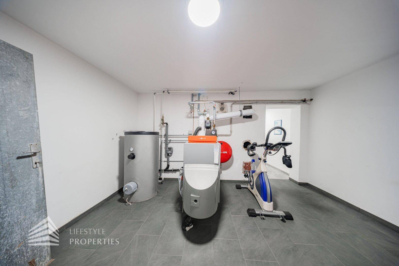 Heizungsraum im Untergeschoss mit Warmwasserspeicher und Fitnessgerät.