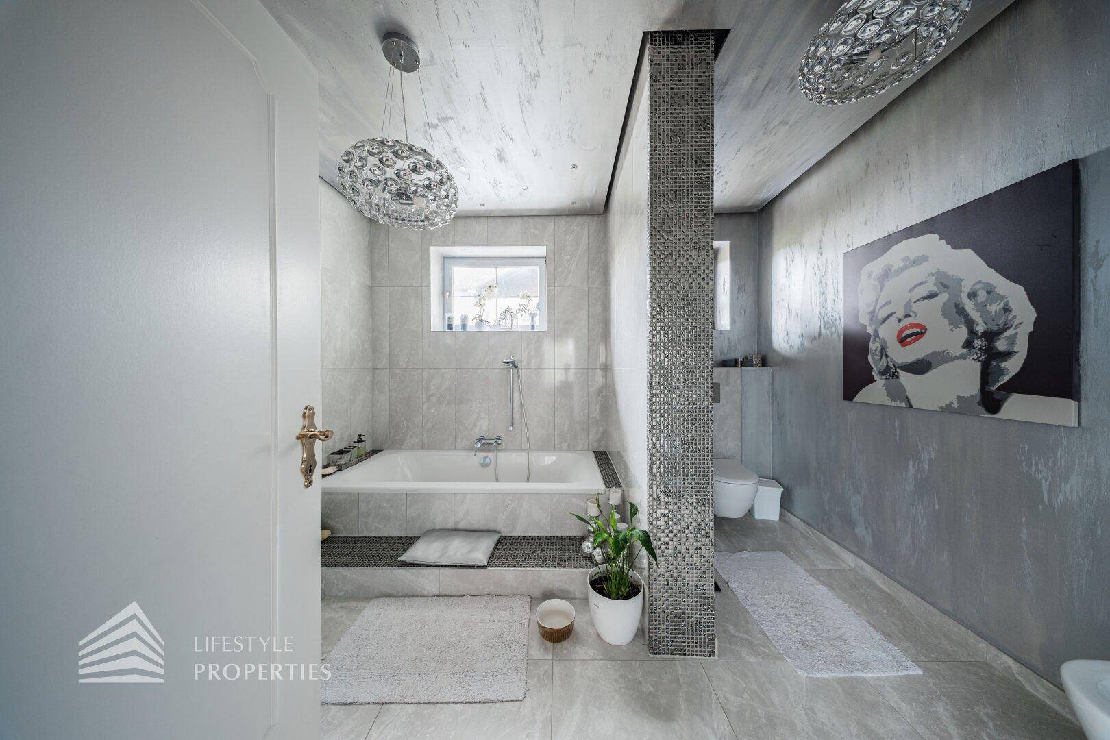 Modernes Badezimmer mit Badewanne, separatem WC und stilvoller Beleuchtung.
