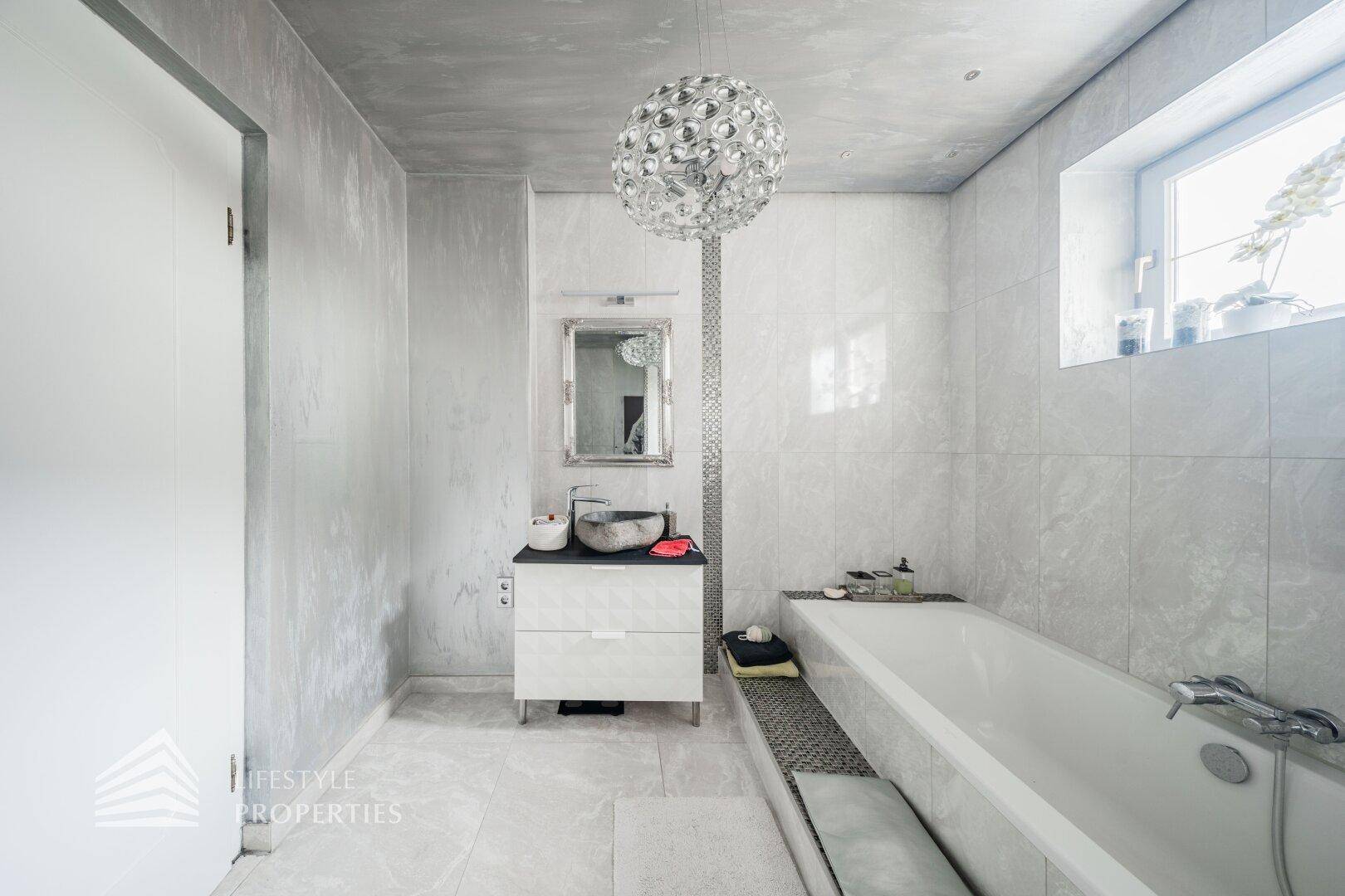 Elegantes Badezimmer mit Badewanne, modernem Waschbecken und stilvoller Beleuchtung.