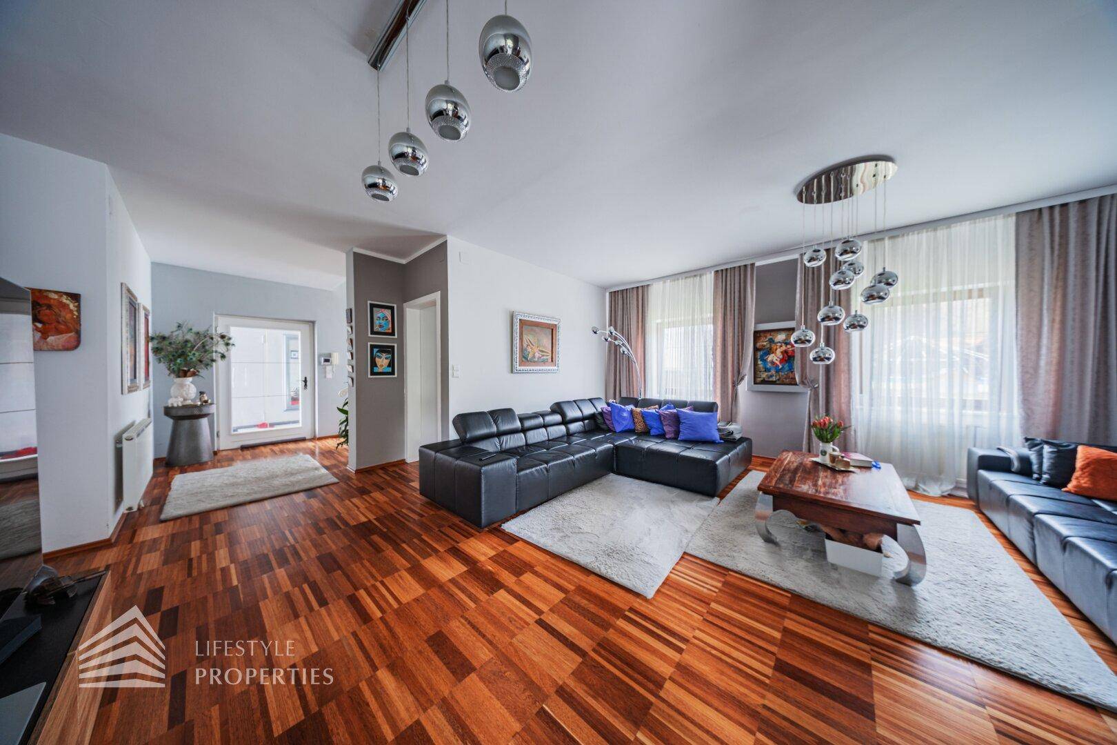 Helles Wohnzimmer mit bequemen Ledersofas, Holzboden und großen Fenstern.