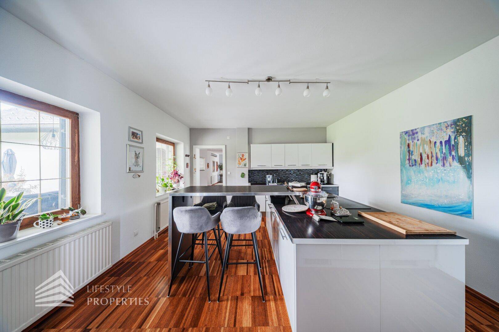 Moderne Küche mit schwarzer Arbeitsplatte, Kücheninsel und Holzboden, ideal für geselliges Kochen.