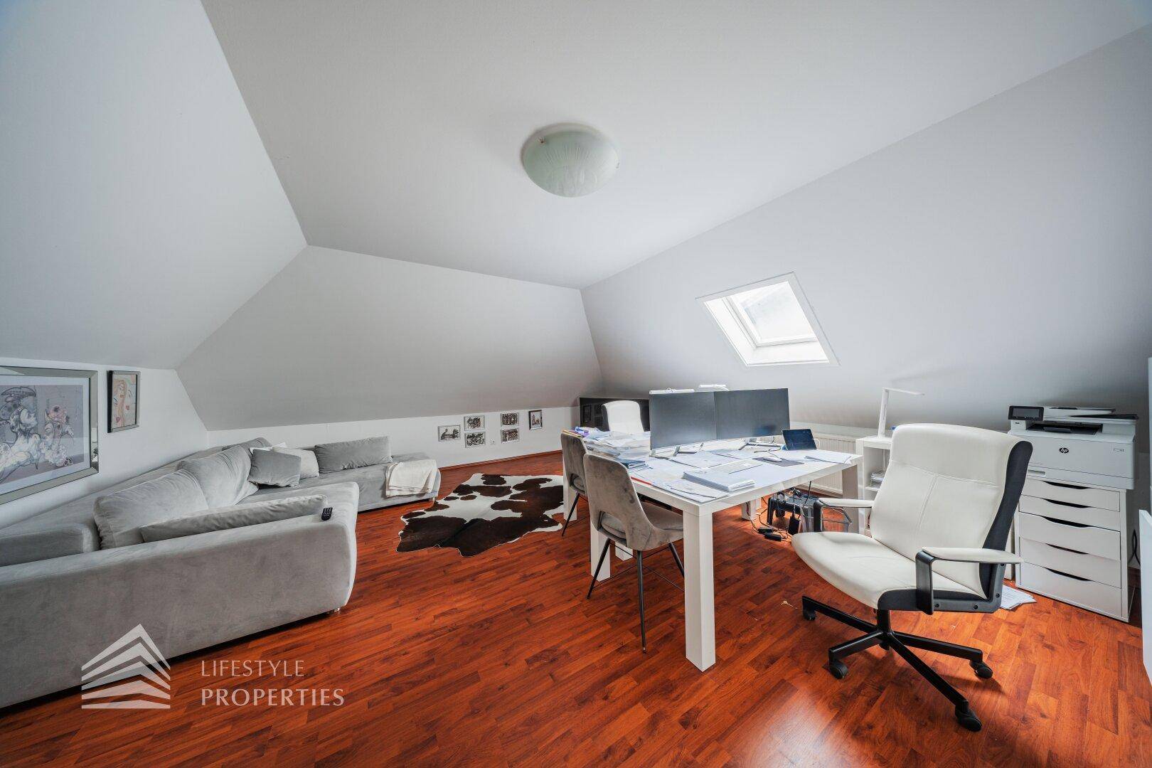 Dachgeschoss-Büro mit Holzboden, Schreibtisch und Dachfenster für viel Tageslicht.