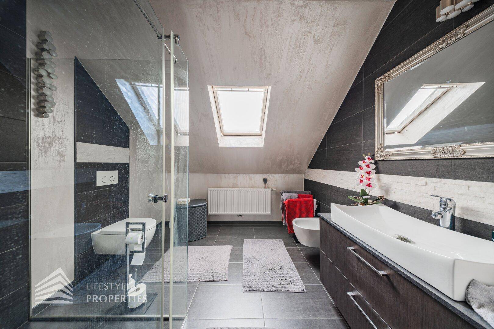Modernes Badezimmer im Dachgeschoss mit Dusche, Doppelwaschbecken und Dachfenster.