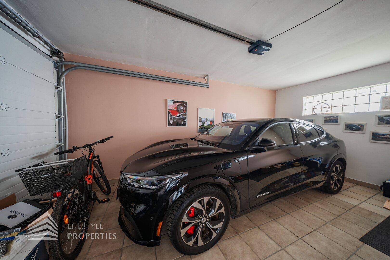 Geräumige Garage mit einem modernen Elektroauto und Fahrrädern, ideal für Fahrzeuge und Lagerung.