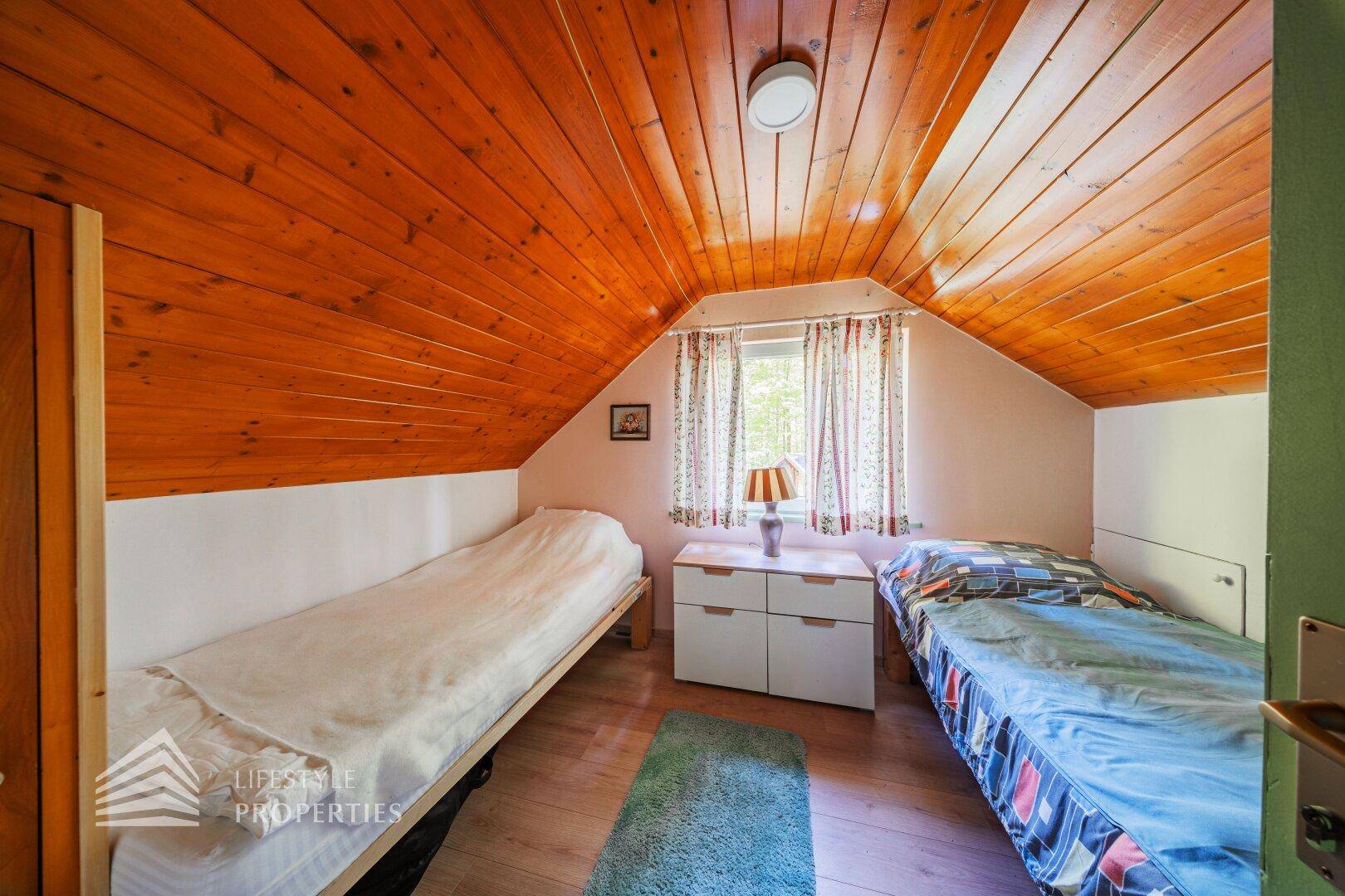 Gemütliches Schlafzimmer im Dachgeschoss mit zwei Einzelbetten und Holzdecke.