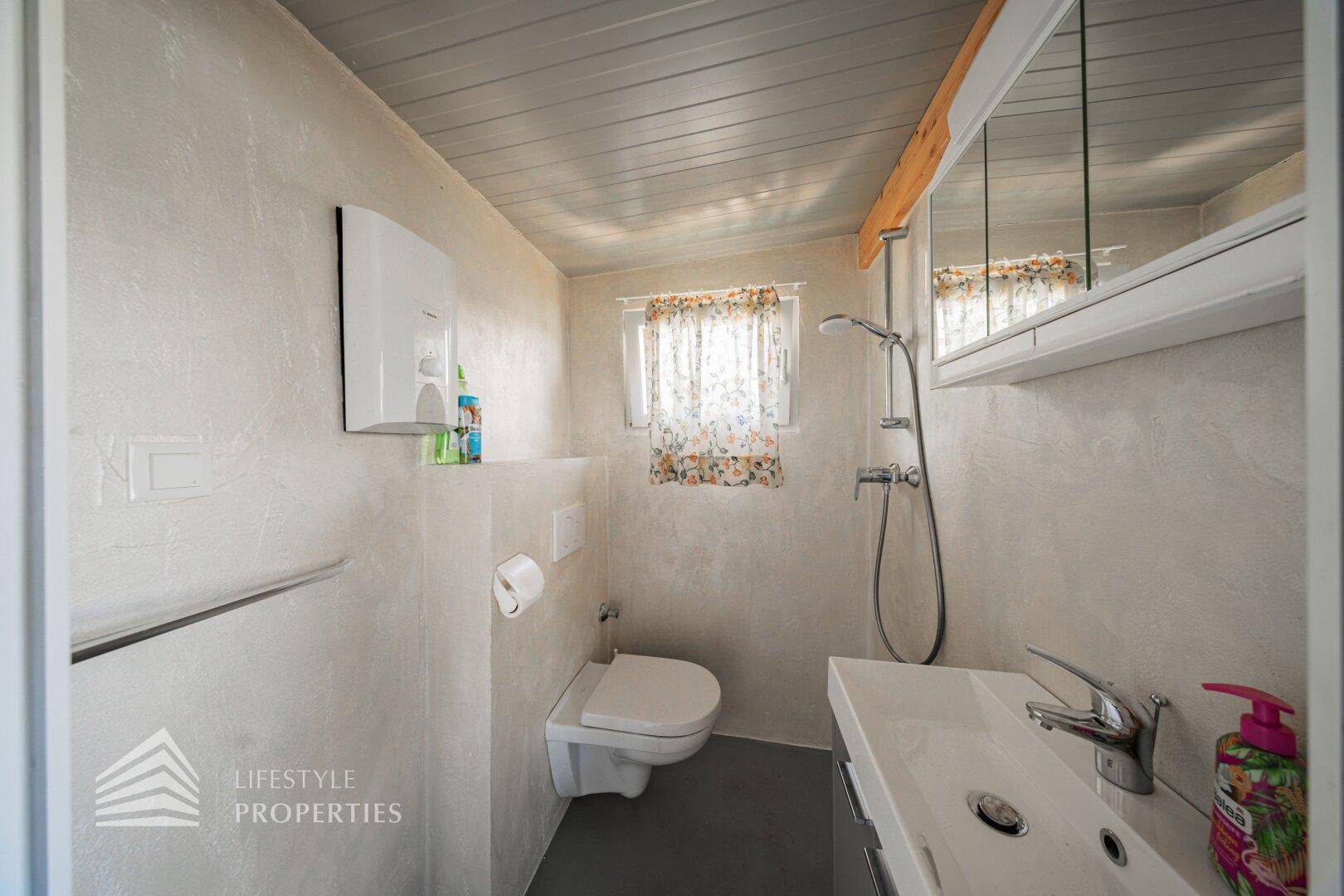 Modernes Badezimmer mit Duschbereich, wandhängendem WC und Waschbecken mit Spiegelschrank.