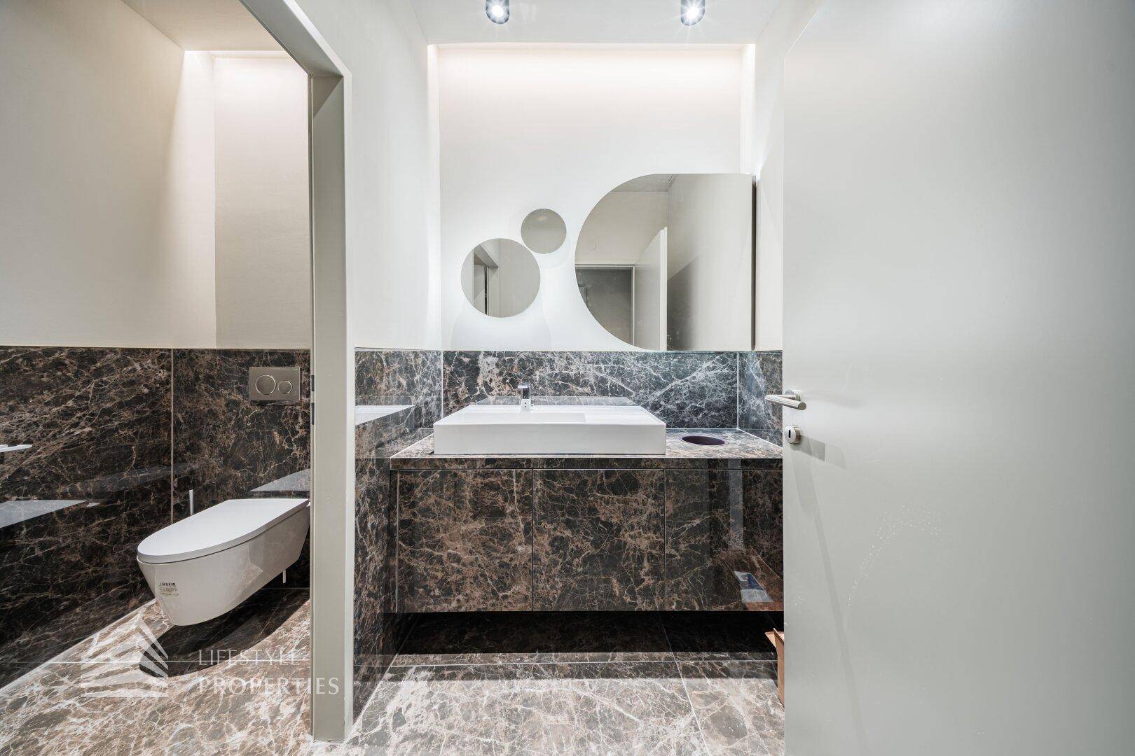 Elegantes Badezimmer mit Marmorfliesen, modernem Waschbecken und Wand-WC.