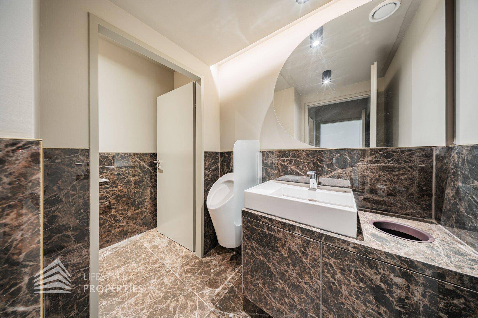 Modernes Badezimmer mit Marmorfliesen, stilvollem Waschbecken und Urinal.