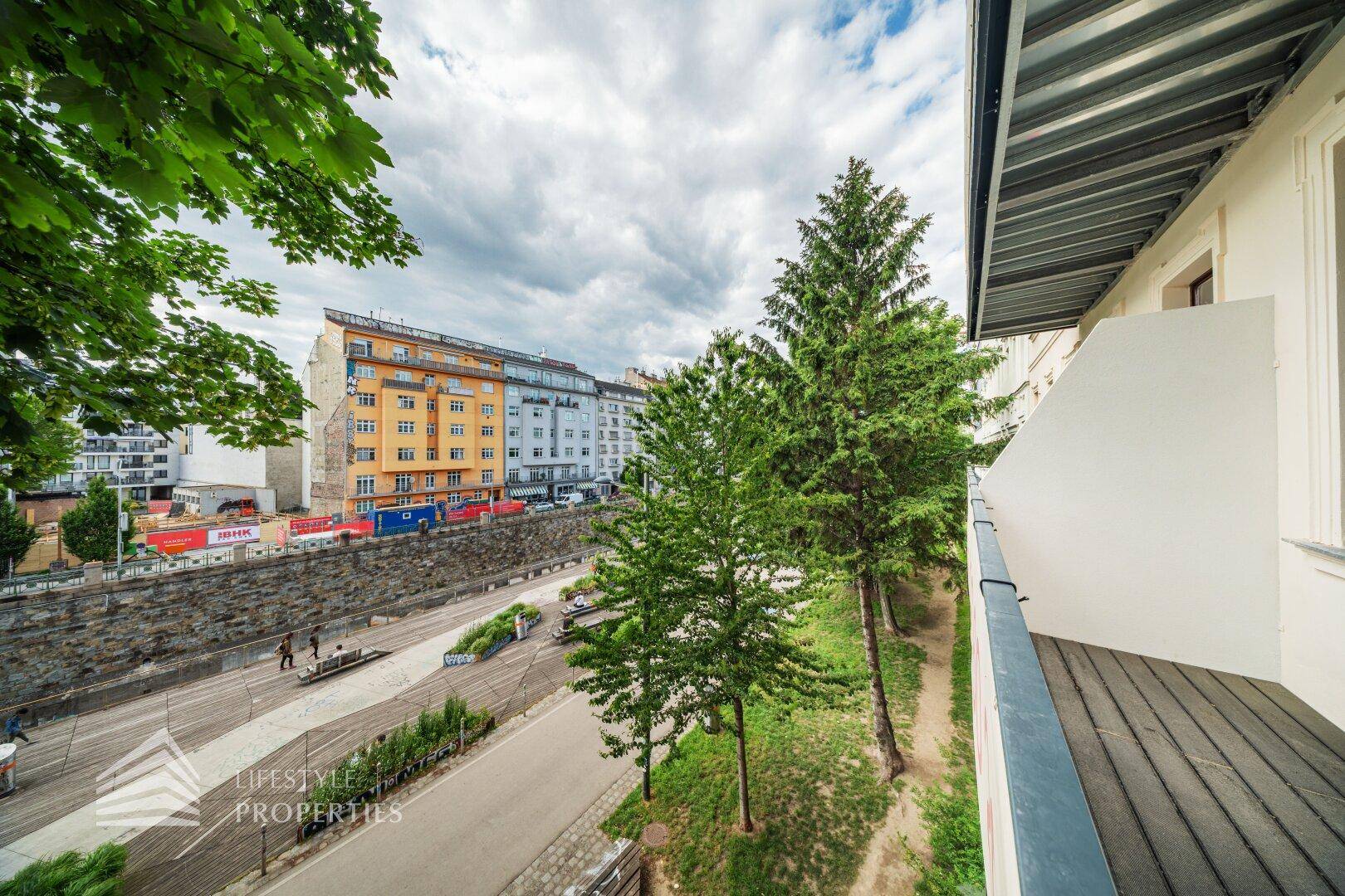 Balkon mit Blick auf die Stadtstraße, Bäume und die gegenüberliegenden Gebäude.