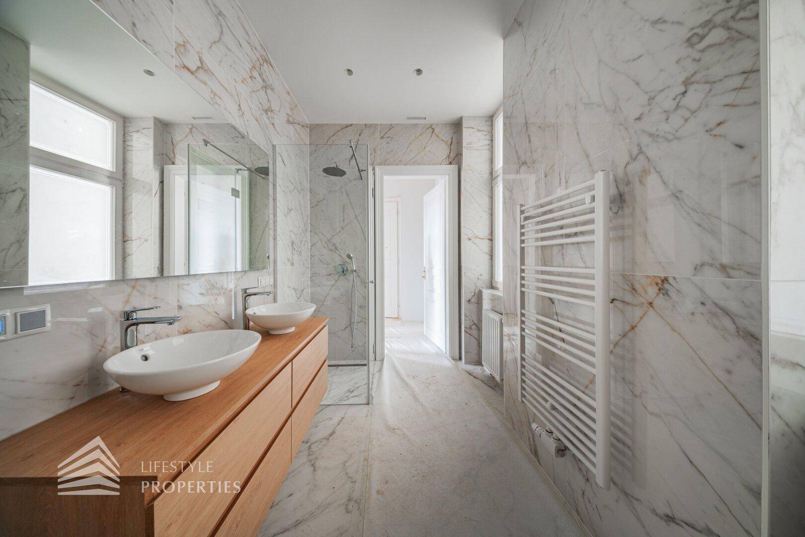 Elegantes Badezimmer mit Marmoroberflächen, Doppelwaschbecken und einer begehbaren Dusche.