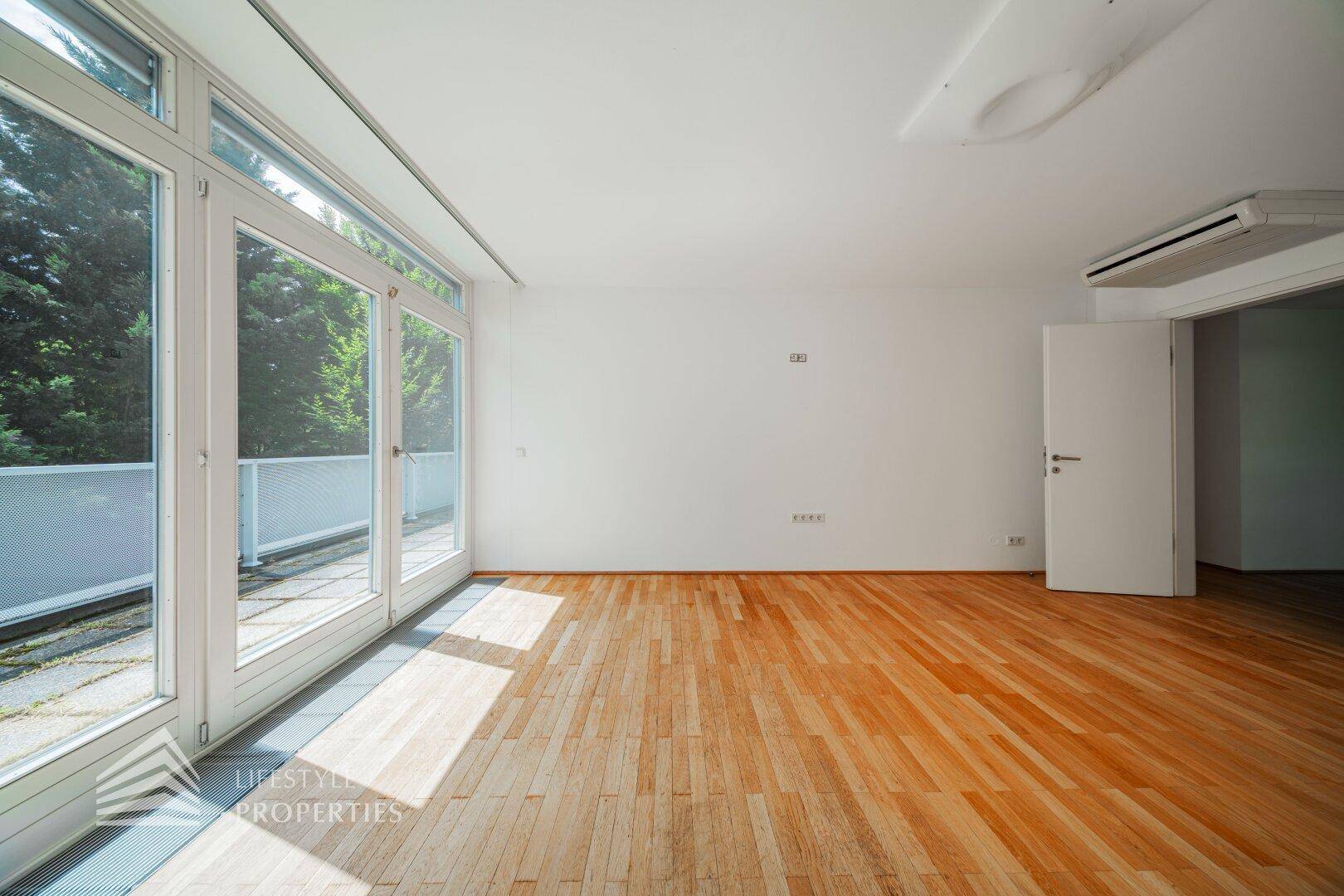 Geräumiges Schlafzimmer mit Holzboden, Klimaanlage und Zugang zur Terrasse.