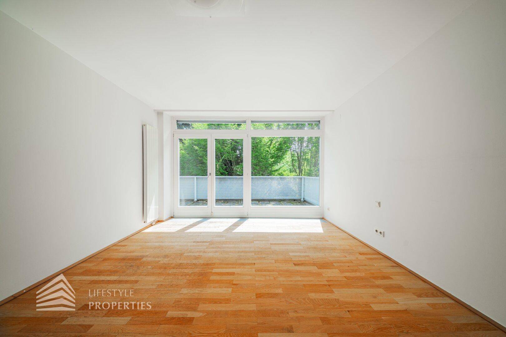 Helles Schlafzimmer mit Holzboden und großzügigem Zugang zu einem Außenbereich.