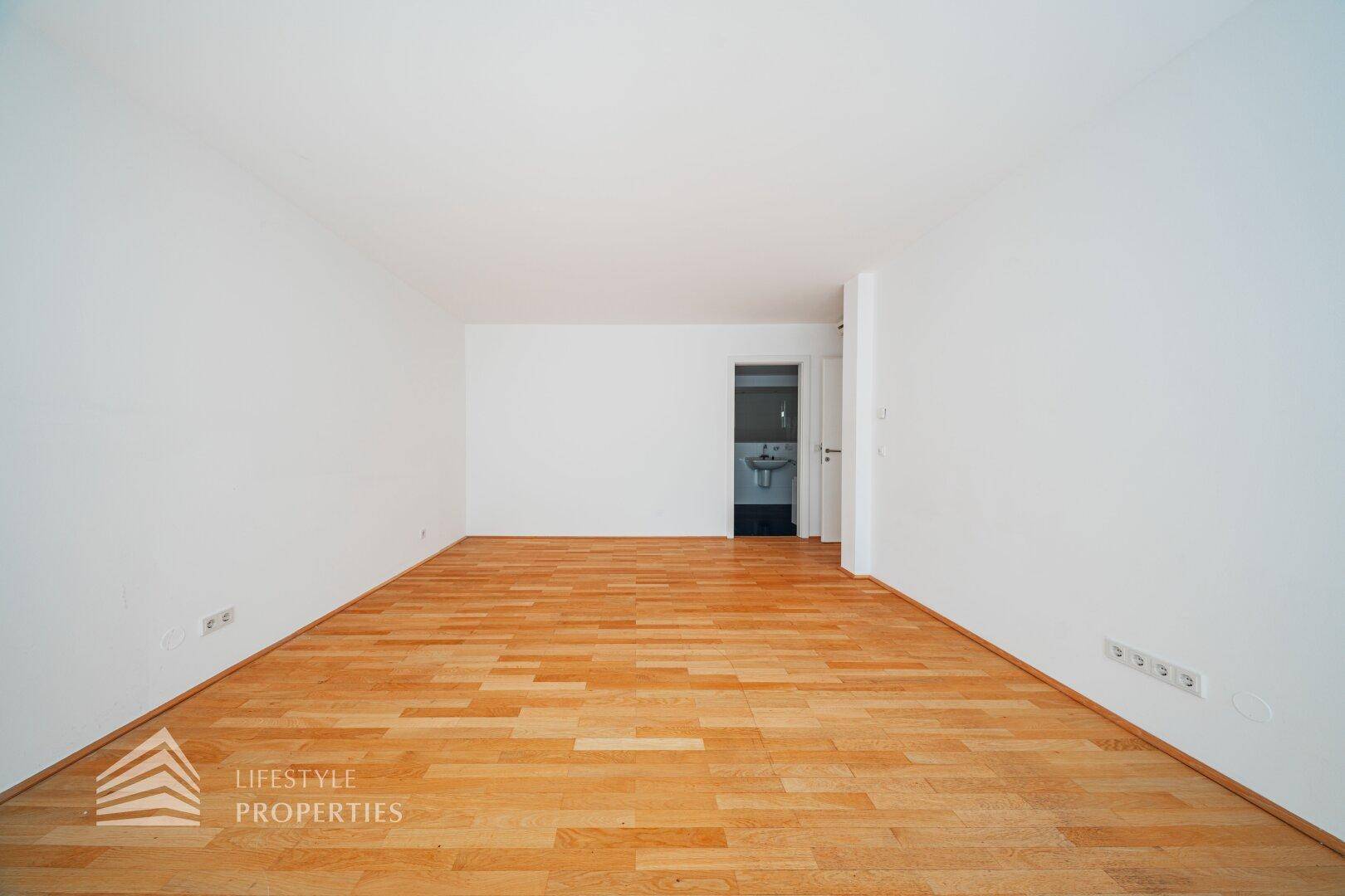 Schlafzimmer mit Holzboden und direktem Zugang zu einem Badezimmer.