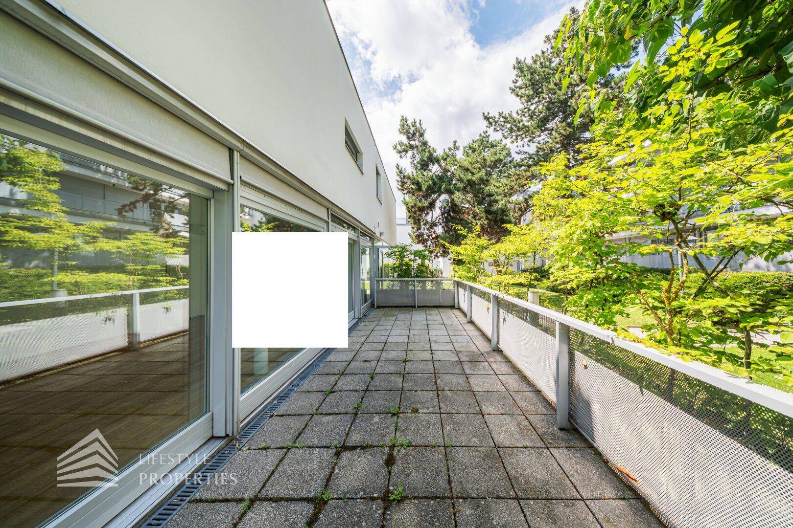 Geräumige Terrasse mit Steinplatten und viel Grün, ideal für Entspannung im Freien.