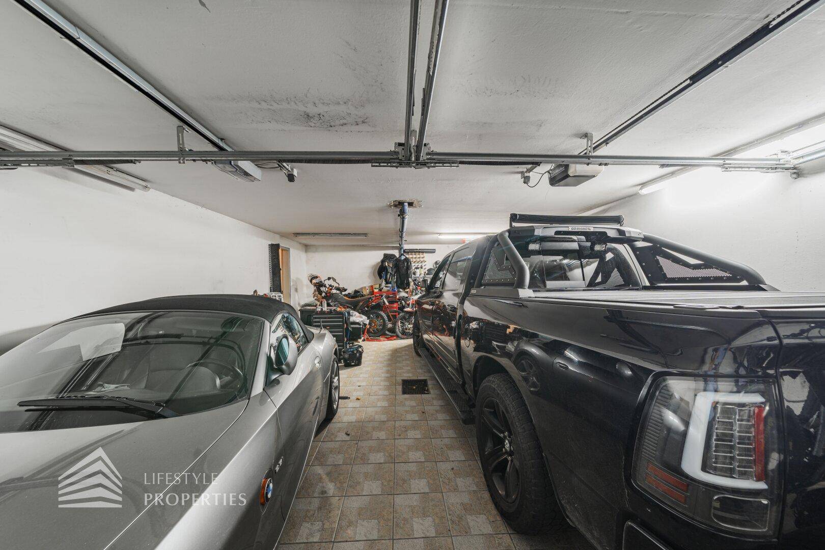 Geräumige Garage mit zwei Fahrzeugen und Stauraum für Motorräder.