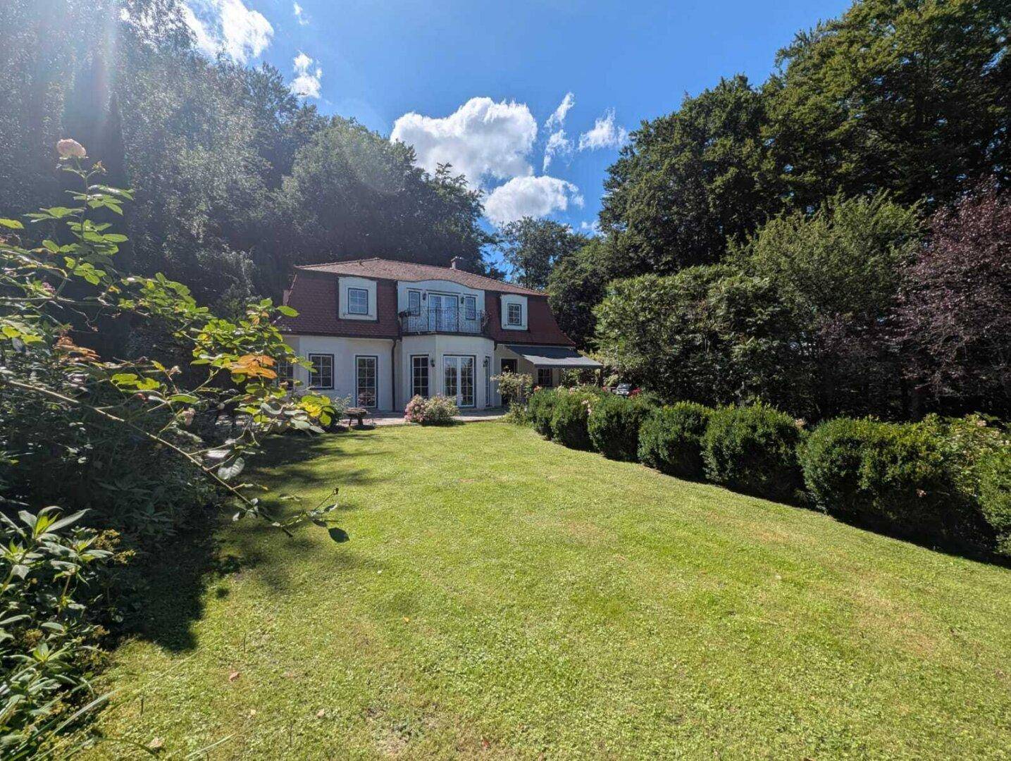 Idyllischer Gartenbereich mit weitläufigem Rasen und Blick auf die elegante Villa.