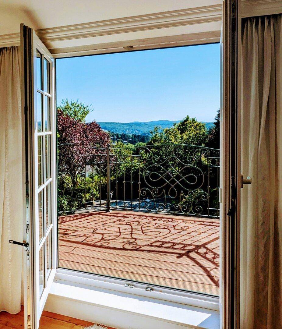 Offener Balkon mit schmiedeeisernem Geländer und weitem Blick über die grüne Landschaft.