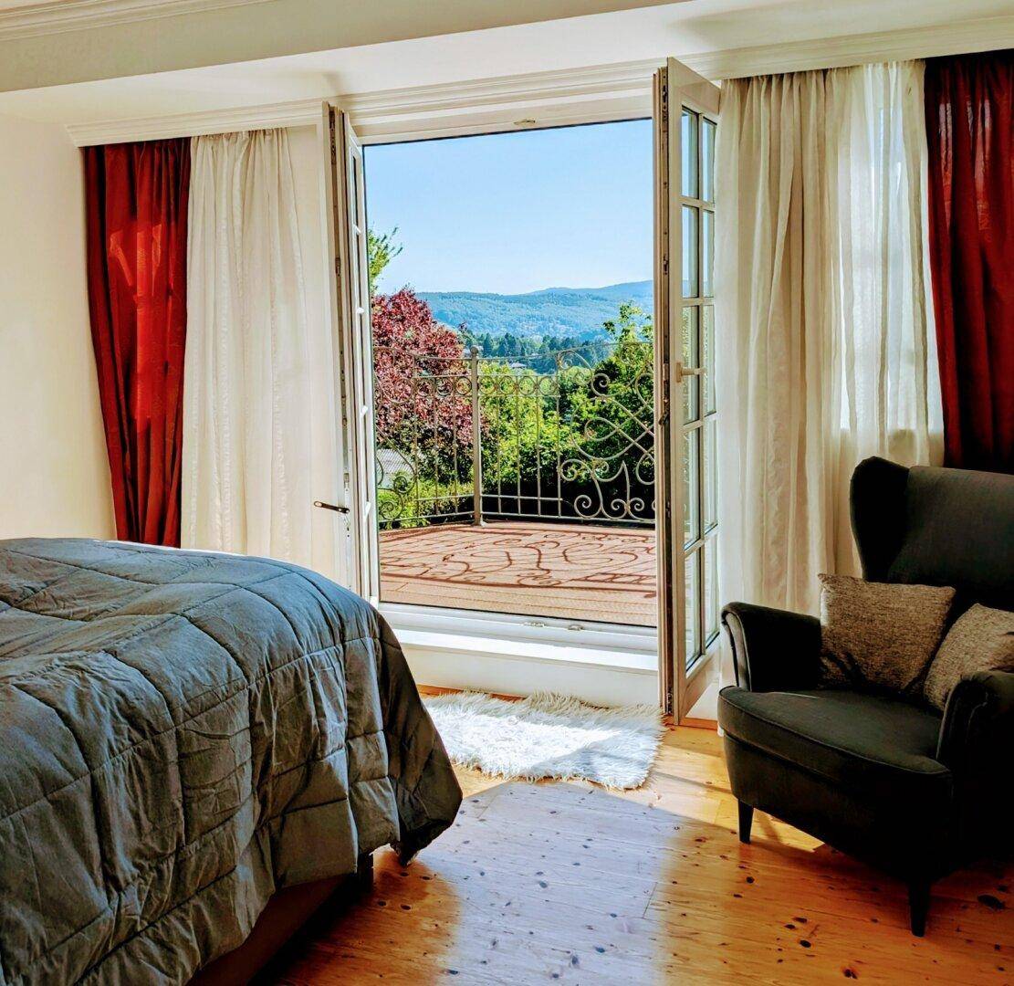 Gemütliches Schlafzimmer mit Balkonzugang und herrlichem Blick auf die umliegende Landschaft.