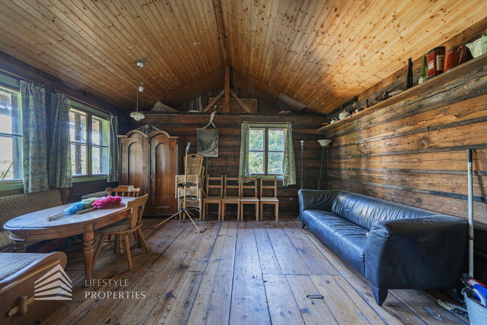 Rustikales Wohnzimmer mit Holzboden, Holzvertäfelung und gemütlicher Einrichtung.