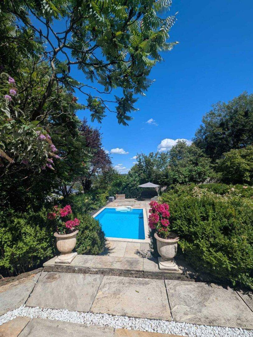 Panoramablick auf den privaten Poolbereich, eingebettet in eine grüne Oase unter blauem Himmel.