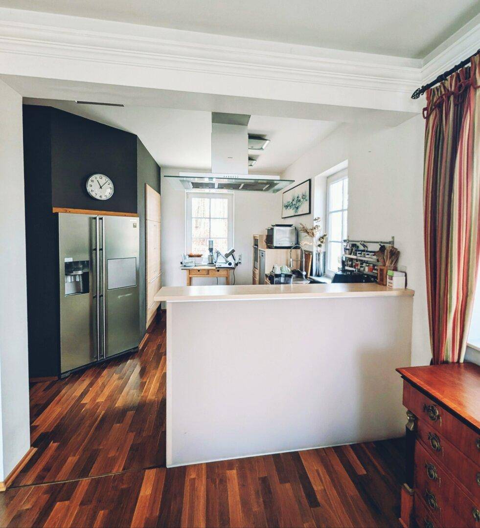 Moderne Küche mit Frühstücksbar, großem Kühlschrank und offenem Übergang zum Wohnbereich.