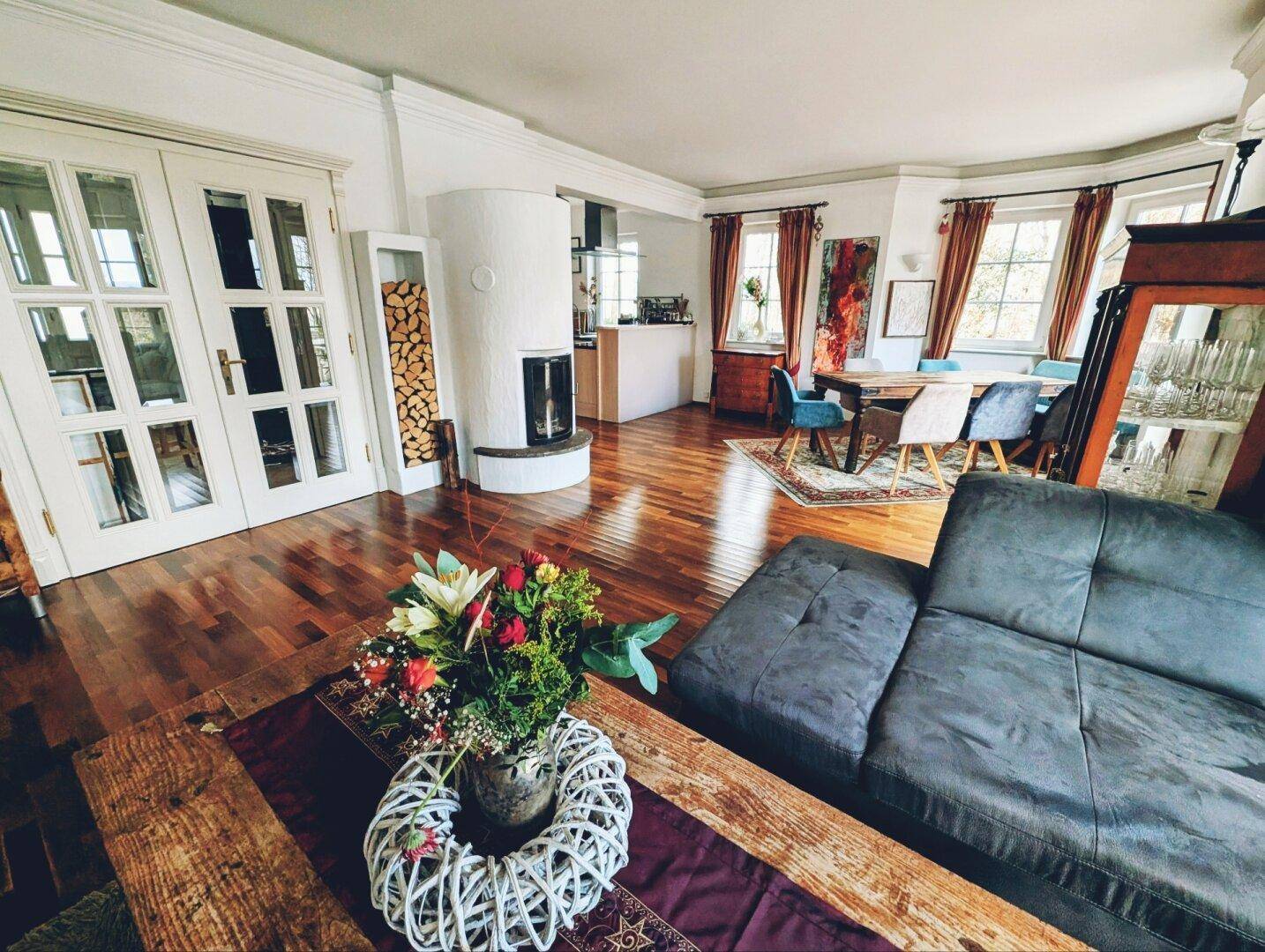 Offener Wohn- und Essbereich mit Kamin, bequemer Couch und elegantem Parkettboden.