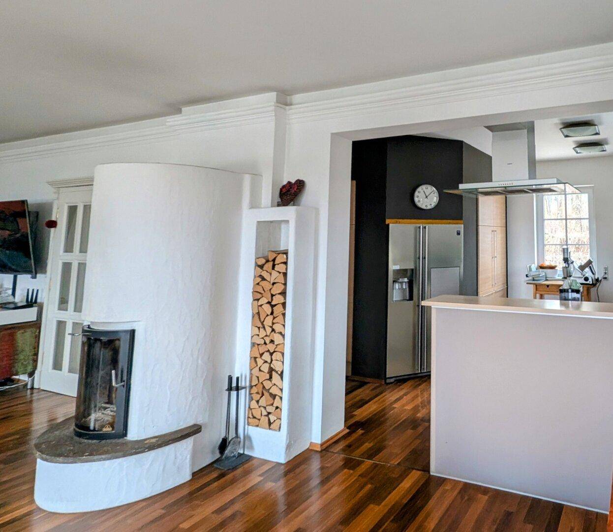 Heller Wohnbereich mit Kamin und offenem Zugang zur modernen Küche mit Frühstücksbar.