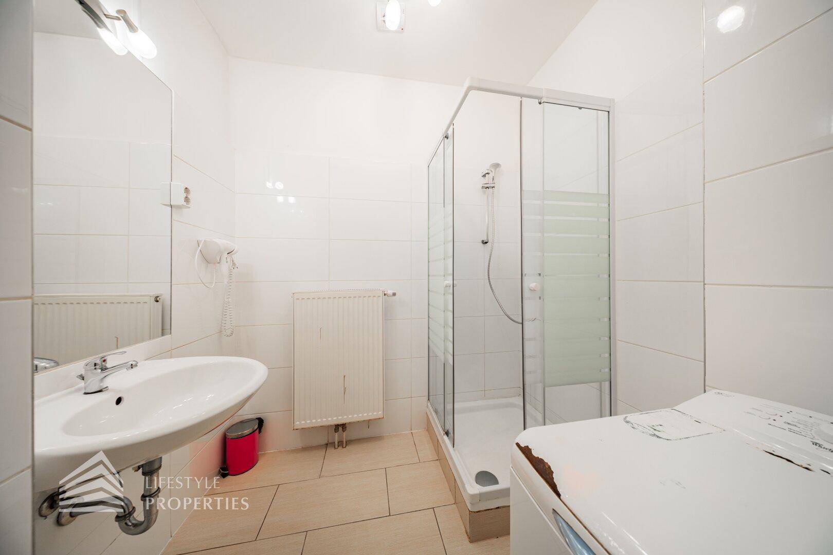 Helles Badezimmer mit Duschkabine, Waschbecken und Waschmaschine.